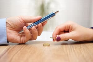 A man giving a pen to a woman to sign the divorce papers